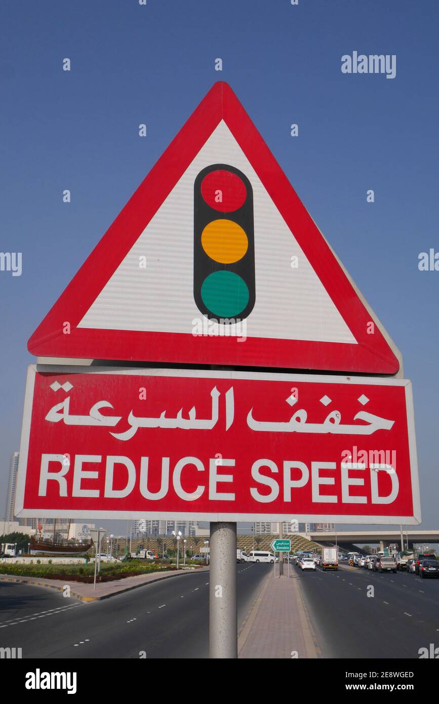 Un panneau en arabe et en anglais indiquant aux automobilistes de réduire la vitesse à cause des feux de signalisation, Manama, Royaume de Bahreïn Banque D'Images