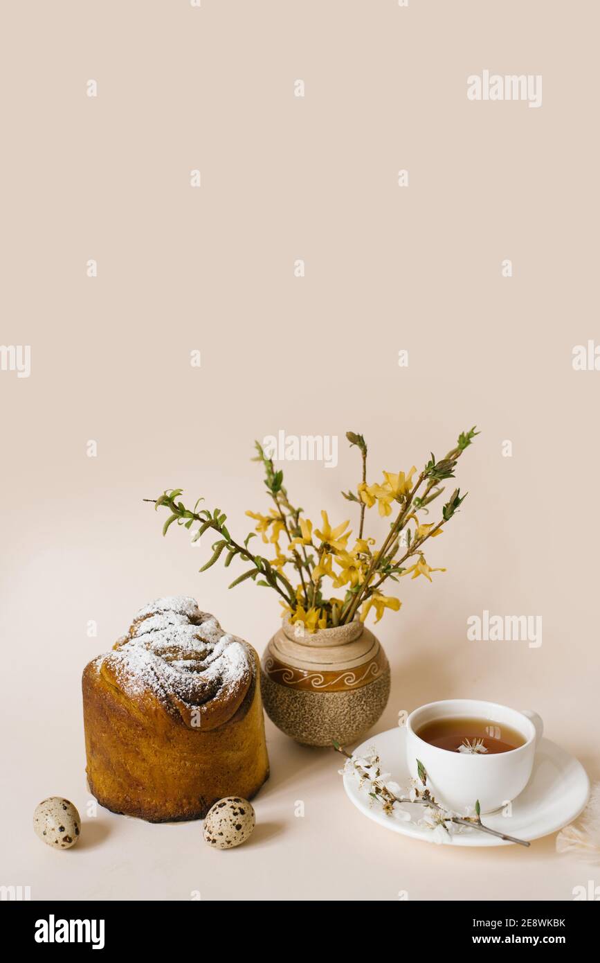 Gâteau de Pâques à l'intérieur. Faites de la spécialité avec des raisins secs, des fruits confits et une saupoudré de sucre. Gâteau fait maison. Oeufs, une tasse de thé et fleurs de printemps dans un v Banque D'Images