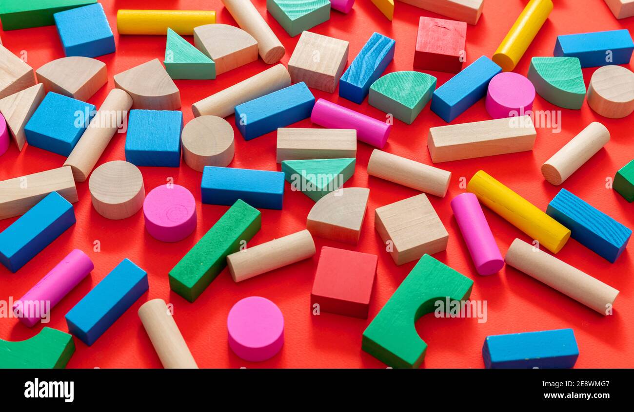 Enfants, enfants créatifs d'âge préscolaire. Cubes en bois colorés sur fond rouge, vue en grand angle. Banque D'Images