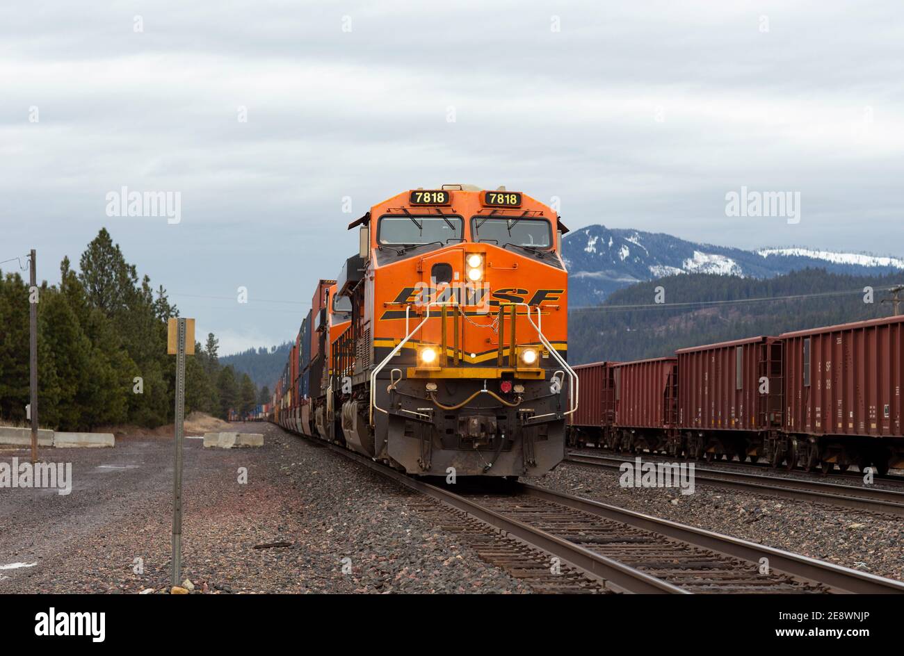 Une locomotive électrique diesel de BNSF tirant une ligne de wagons de puits de conteneurs à travers la cour de chemin de fer à Troy, Montana. Burlington Nord et Santa Banque D'Images