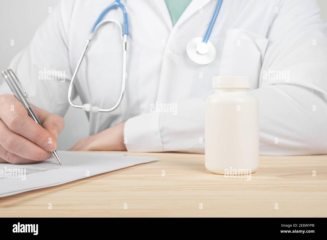 Médecin prescrivant des médicaments. Instructions pour prendre les pilules correctement. Industrie pharmaceutique. Contenant en plastique blanc vierge pour flacons de médicaments. Homme médecin main Hol Banque D'Images