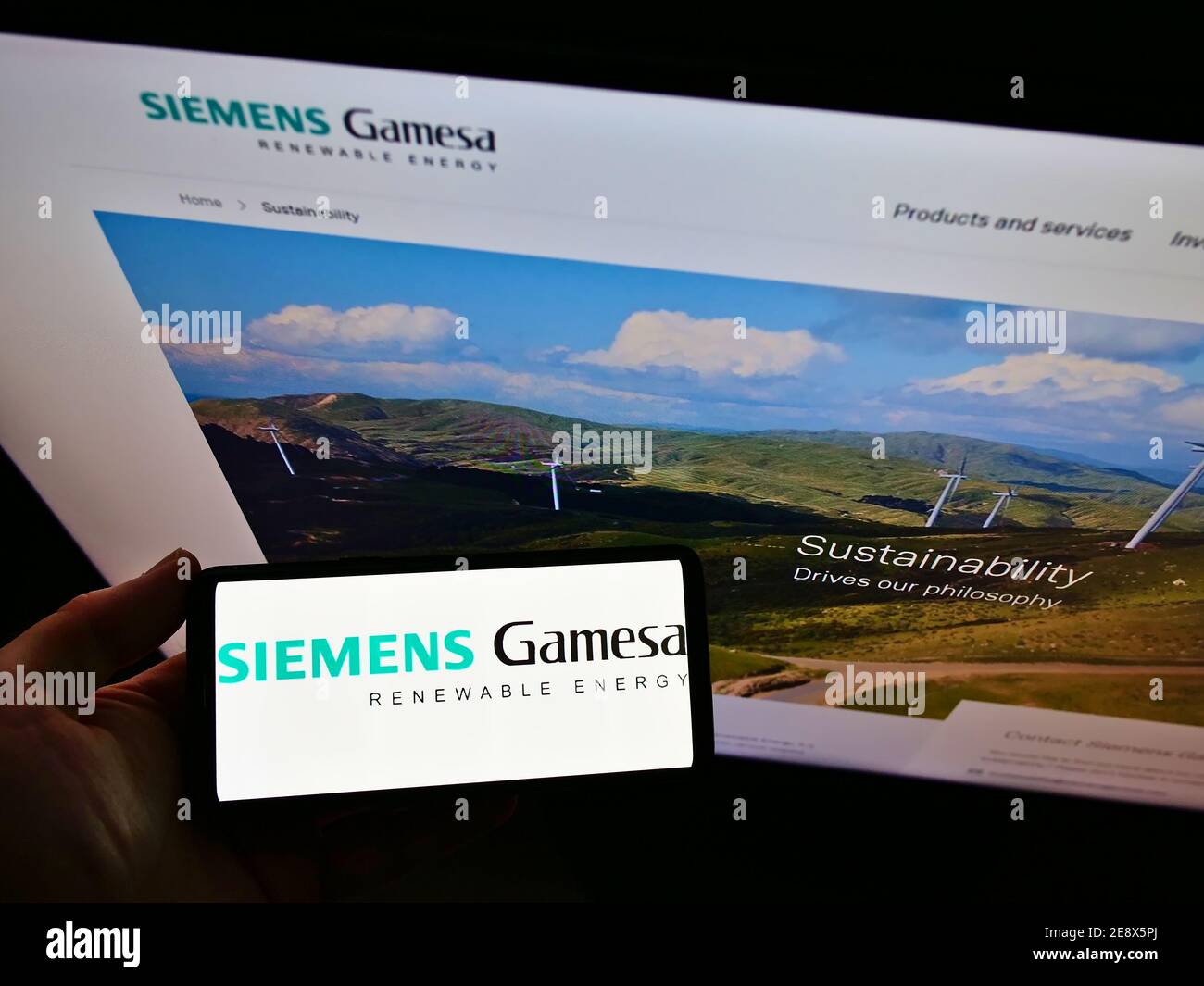 Vue en grand angle de la personne qui tient un smartphone avec le logo de la société d'ingénierie Siemens Gamesa Renewable Energy S.A. sur l'exposition. Mise au point sur l'écran du téléphone. Banque D'Images