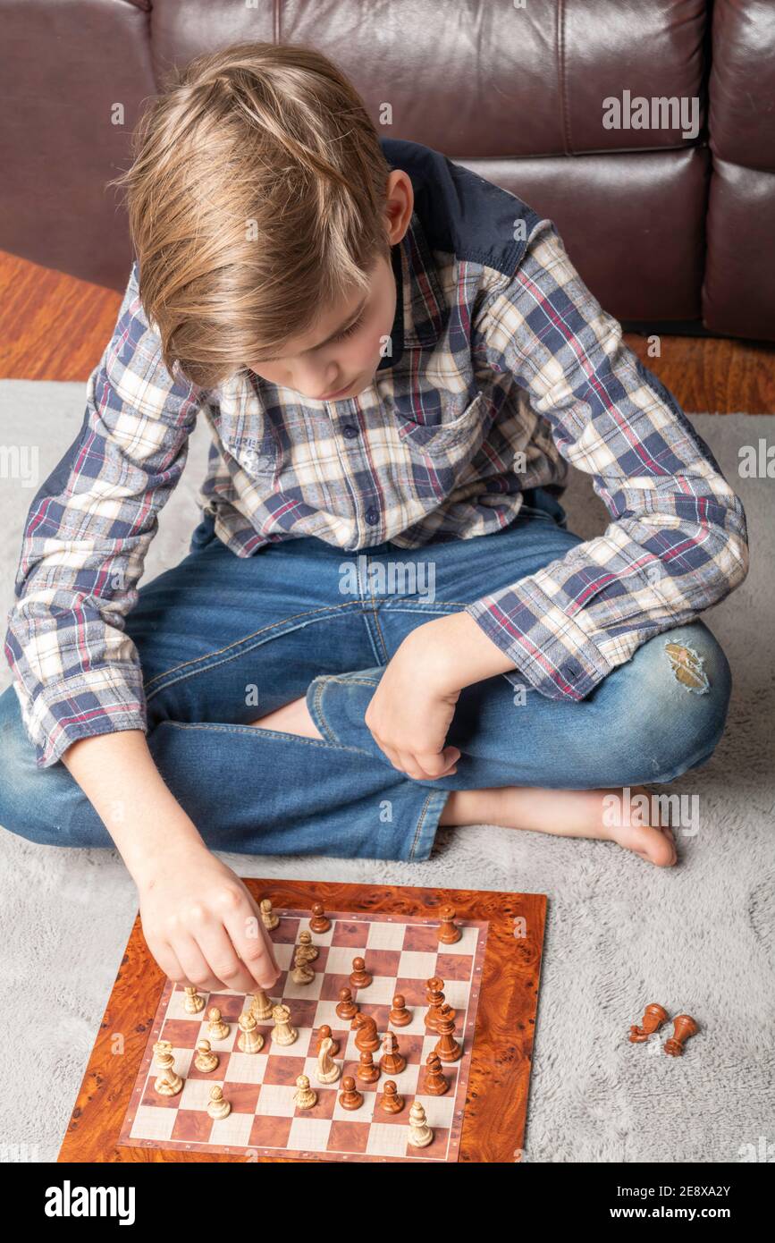 Adolescent caucasien jouant aux échecs dans le tapis gris, l'éducation, l'activité et le hobby à la maison concept Banque D'Images