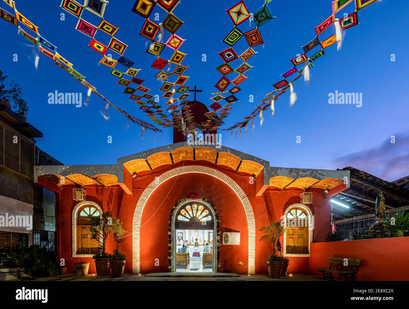 Petite église rouge sur la place avec des bannières Huichol appelées 'Ojos de Dios' volant dans le vent à Sayulita, Nayarit, Mexique. Banque D'Images