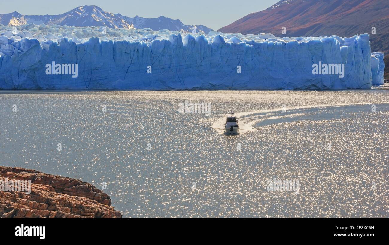 Vue panoramique sur le paysage des glaciers avec bateau touristique éblouissez la surface floue du lac dans l'éblouissement du soleil près de célèbre Fusion du glacier Perito Moreno Banque D'Images