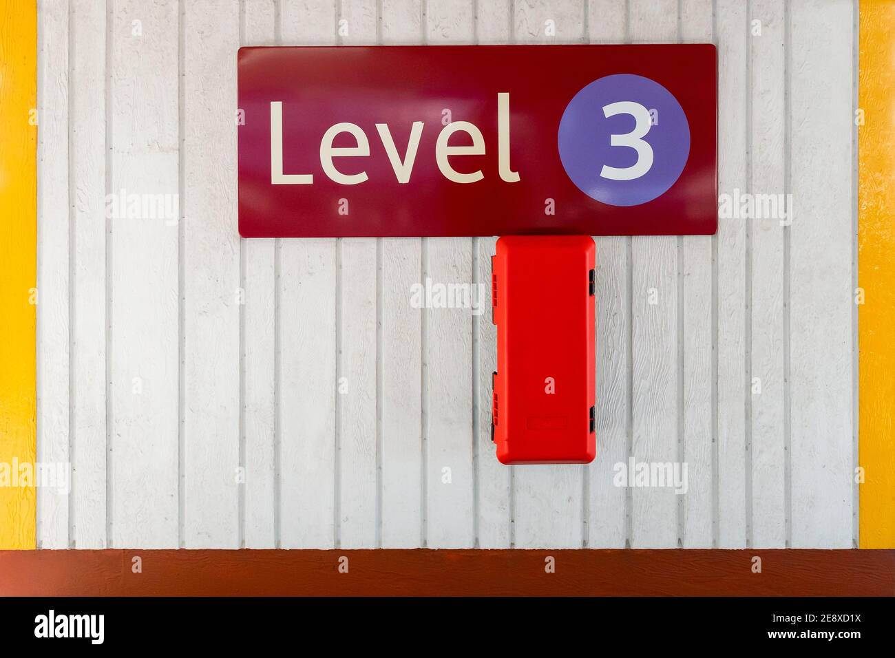 Affiche de niveau trois portant le numéro 3 dans un cercle bleu mur en béton avec boîte d'extincteur au troisième étage de parking moderne et propre sur plusieurs étages Banque D'Images