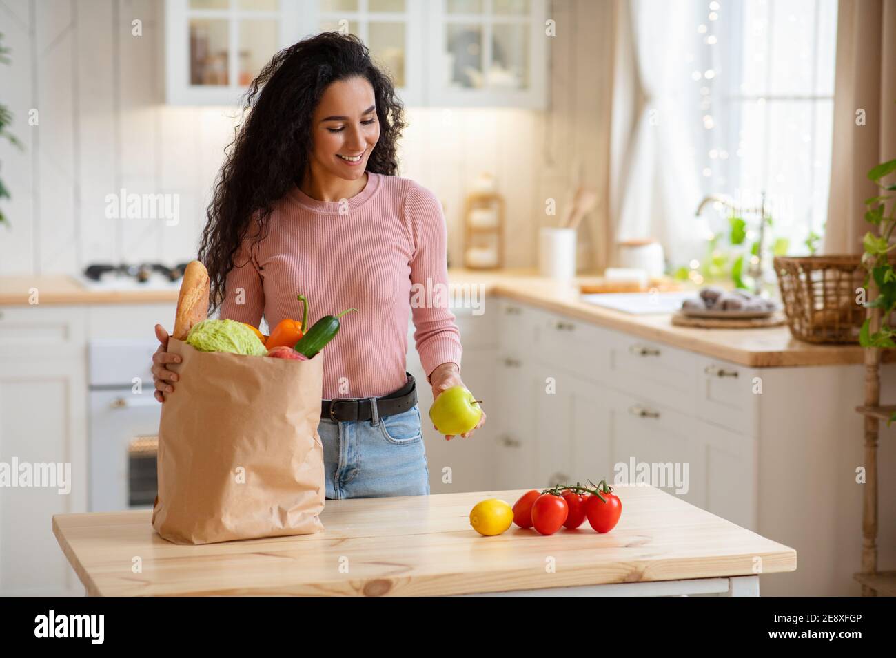 Jeune femme Déballage sac de papier avec légumes et fruits après Épicerie Banque D'Images