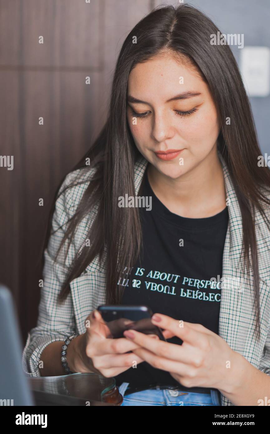 Jeune femme vérifiant et tapant sur son téléphone cellulaire. Vérifier leurs réseaux sociaux et publier des photos. Banque D'Images