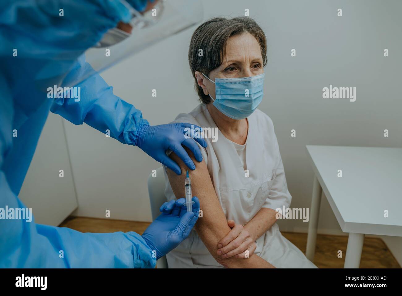 Médecin dans l'ensemble de protection et les gants faisant la vaccination COVID-19 Banque D'Images