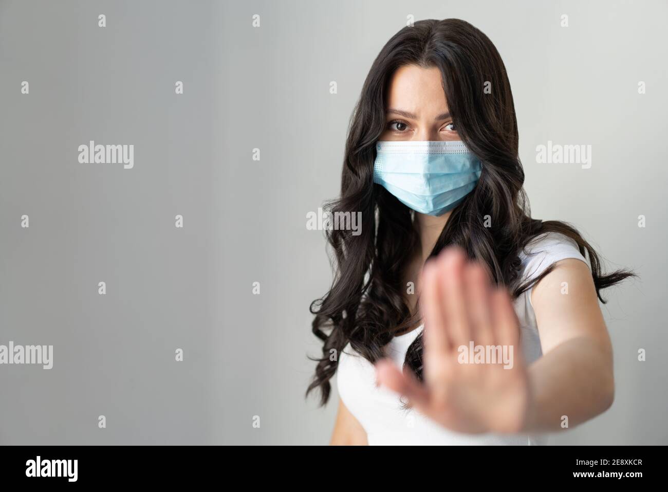 Femme portant un masque pour la protection contre la maladie et montre mains stop geste pour arrêter l'épidémie de virus corona. Un attrait pour rester à la maison. Concept de coronavirus. Banque D'Images