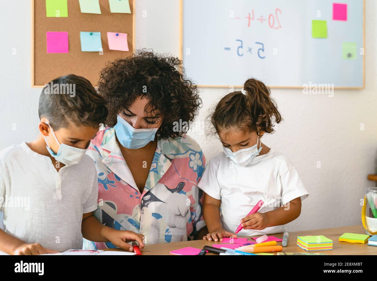 Enseignant avec des enfants portant un masque facial dans la salle de classe préscolaire pendant pandémie de virus corona - concept de soins de santé et d'éducation Banque D'Images