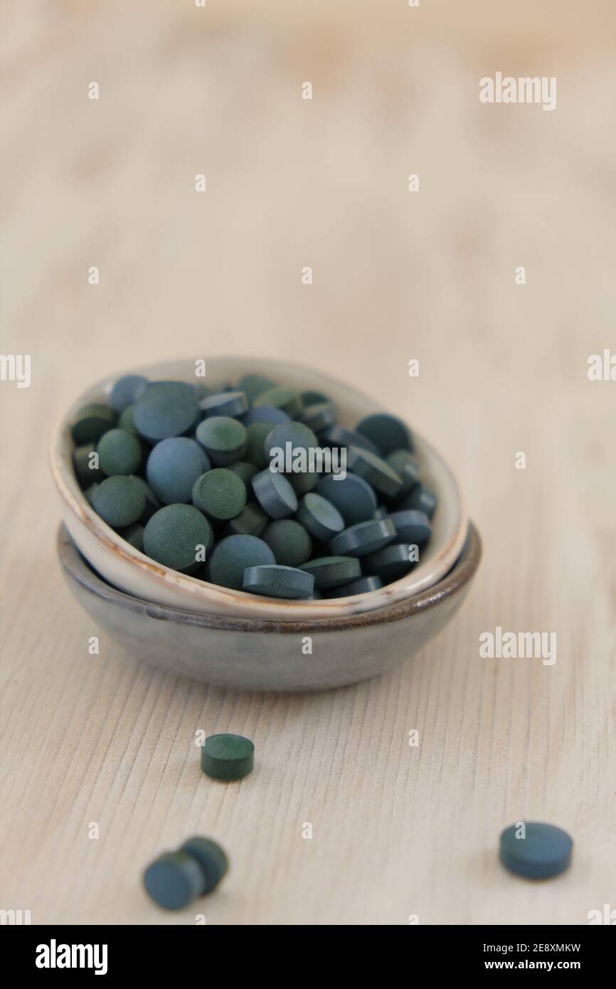 Spiruline algue vert en comprimés dans des tasses rondes en céramique sur un fond en bois clair..Suppléments diététiques.Super nourriture. Algue biologique saine.saine Banque D'Images