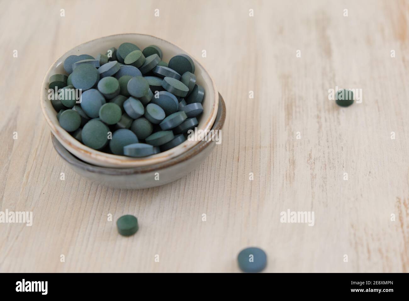 Spiruline algue vert en comprimés dans des tasses rondes en céramique sur un fond de bois clair..Suppléments diététiques.Super nourriture. Algues biologiques saines Banque D'Images
