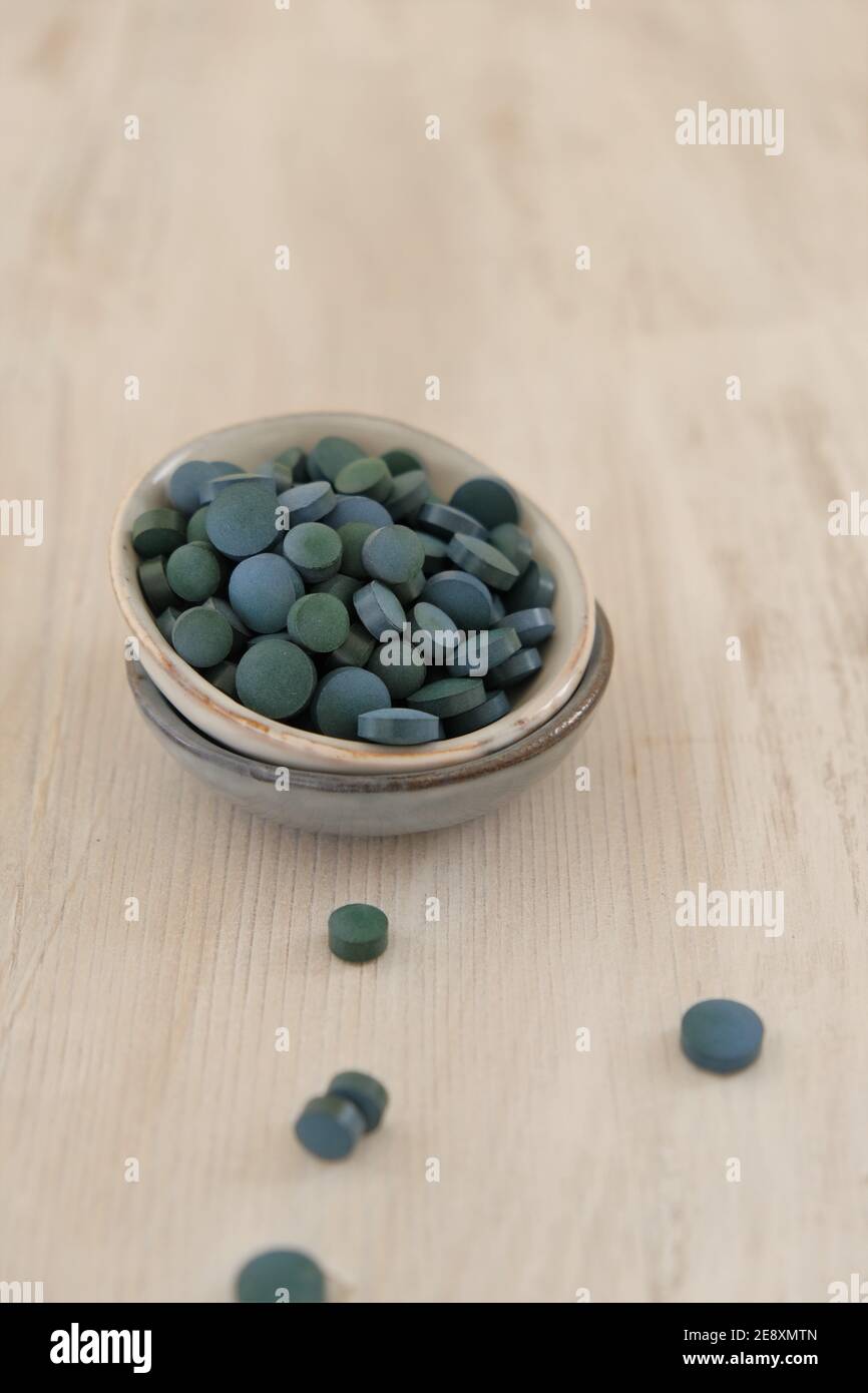 Spiruline algue vert en comprimés dans des tasses rondes en céramique sur un fond de merde en bois..Suppléments diététiques.Super nourriture. Algue biologique saine.saine Banque D'Images