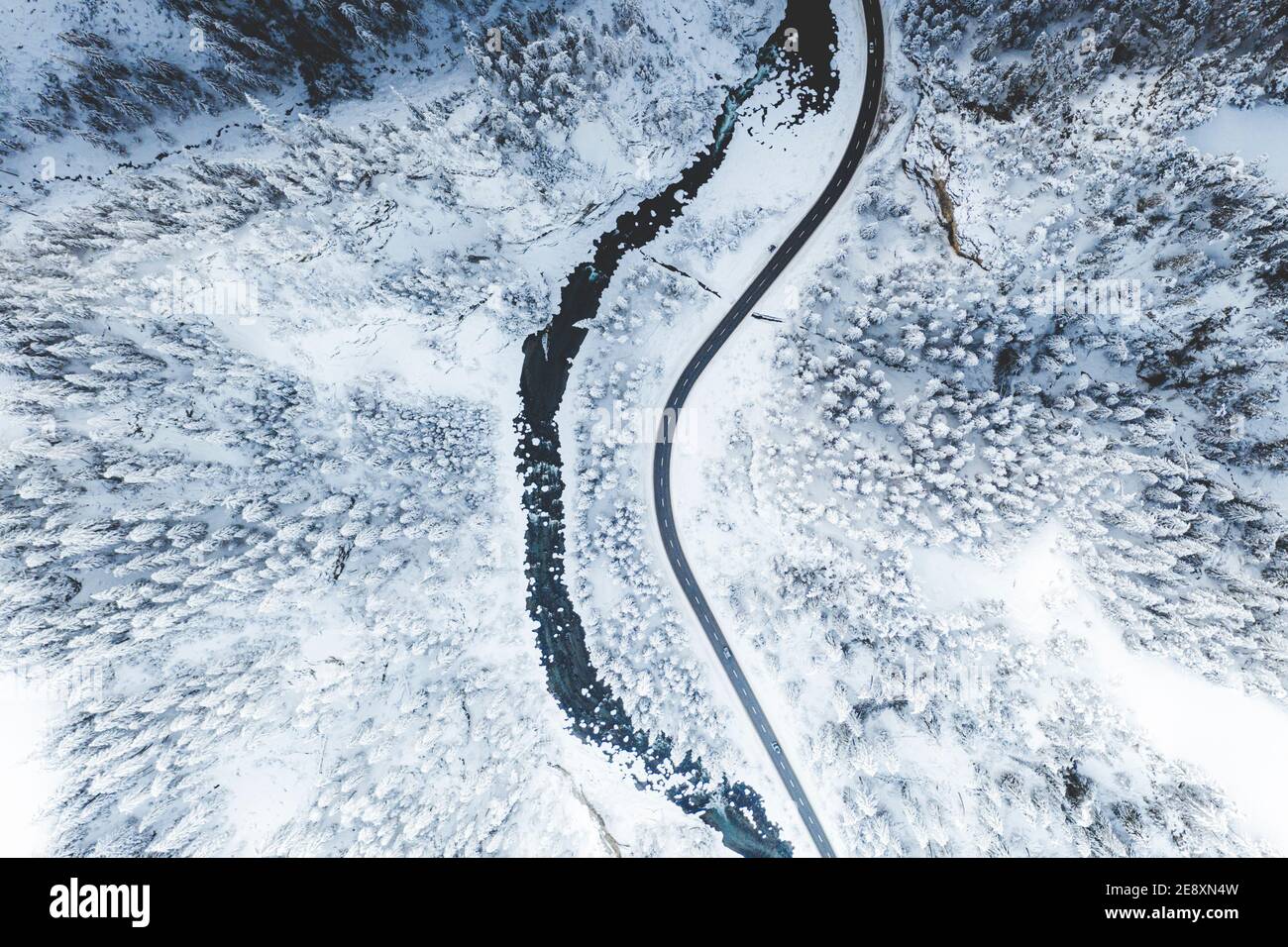 Route sinueuse longeant une rivière gelée dans la forêt d'hiver couverte de neige, vue aérienne, Suisse Banque D'Images