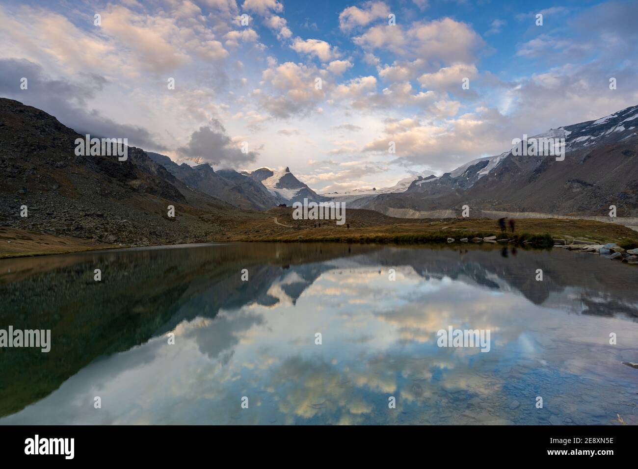 Randonneurs marchant sur les rives du lac Stellisee vers la cabane de montagne Fluhalp, Zermatt, canton du Valais, Suisse Banque D'Images