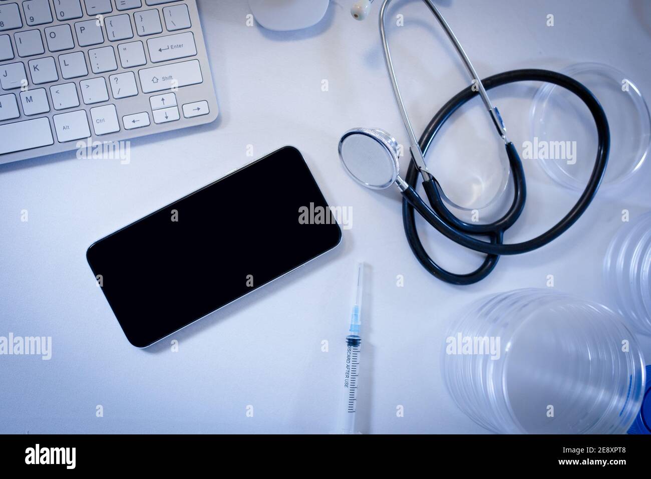 Bureau en chirurgie de médecins avec smartphone ordinateur clavier seringue et stéthoscope Banque D'Images