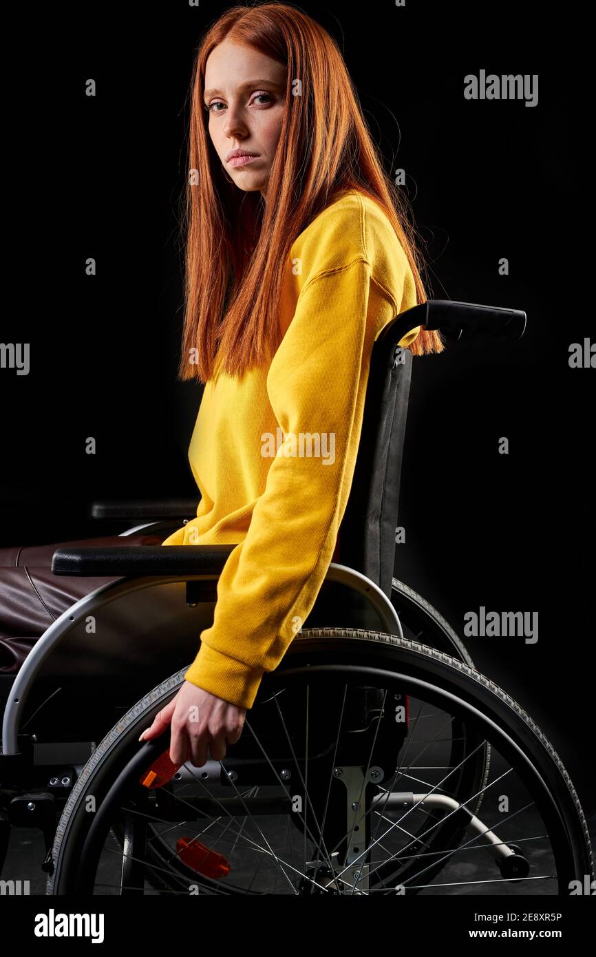 triste femme handicapée dans un fauteuil roulant, regardant la caméra  enfoncée. redhead femme en jaune chemise décontractée est isolée sur fond  noir. santé et p Photo Stock - Alamy