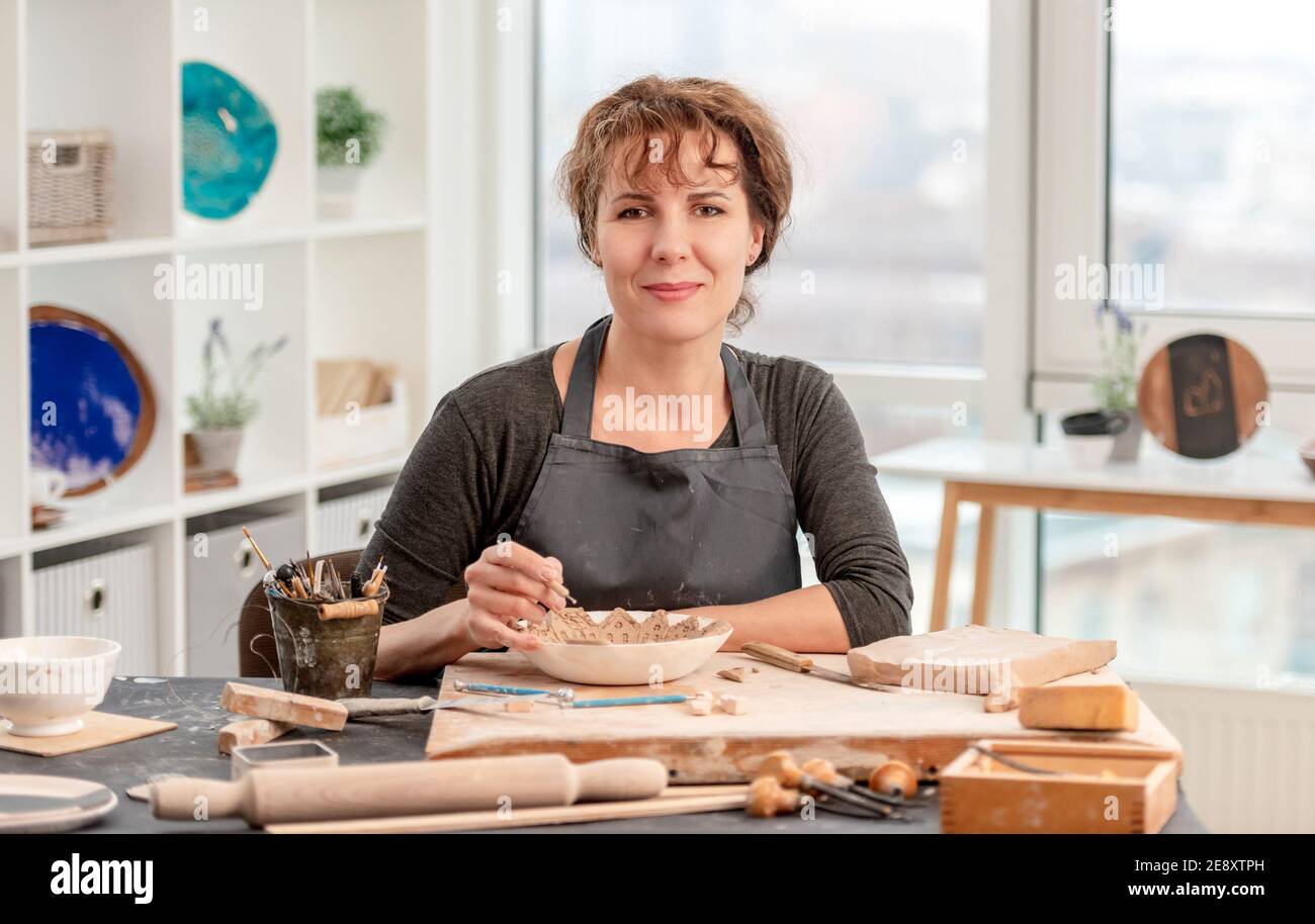 Femme assise à table avec poterie Banque D'Images