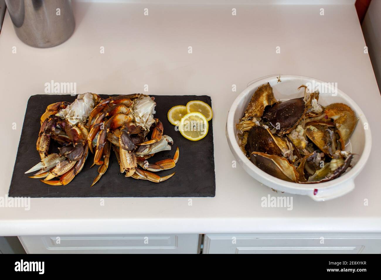 Les pattes de crabe dormeur sont nettoyées et préparées pour le dîner. Les gouts et les coquilles de crabe sont jetés dans un bol à côté d'eux. Banque D'Images