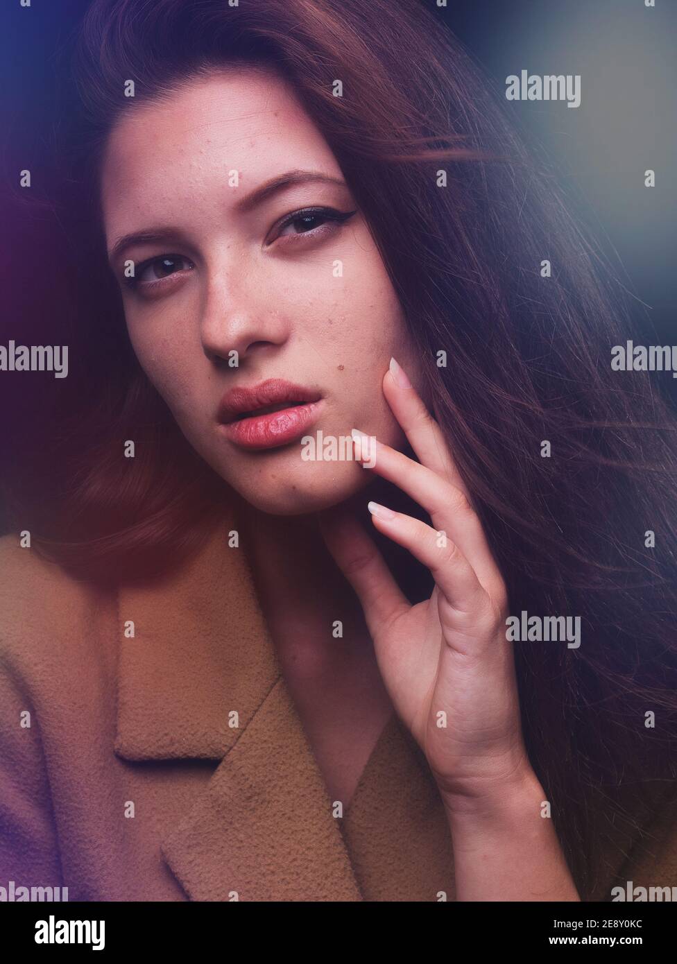 sexy et belle jeune femme regardant l'appareil photo, posant dans un manteau ambre, même couleur que son teint de peau. Arrière-plan noir dans le studio photo. Photo colorée Banque D'Images