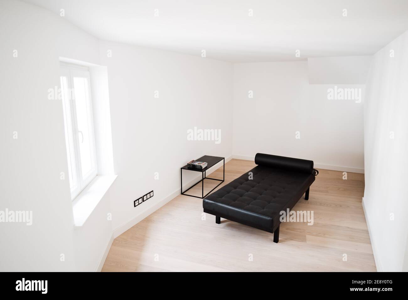 un canapé-lit moderne noir dans une chambre blanche Banque D'Images