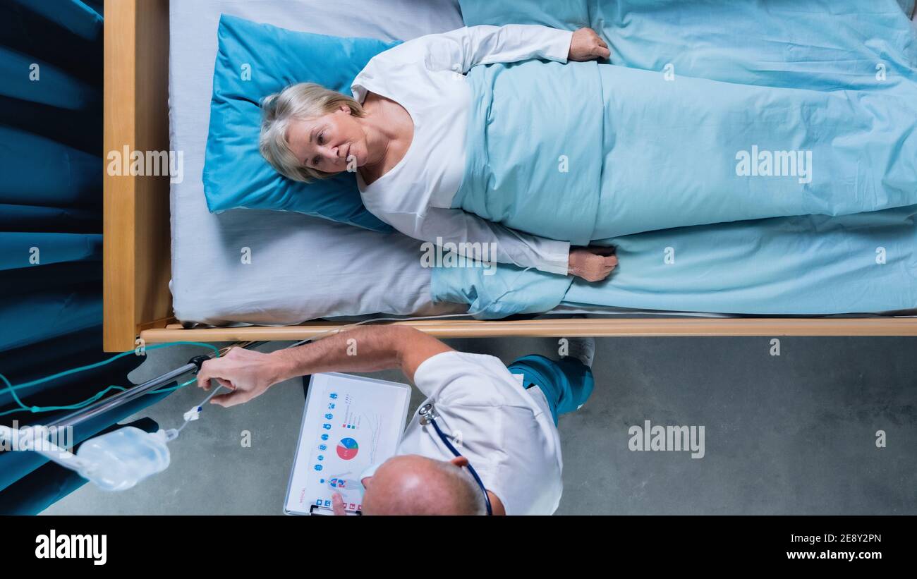 Vue de dessus du médecin et de la patiente avec perfusion IV dans le lit à l'hôpital. Banque D'Images