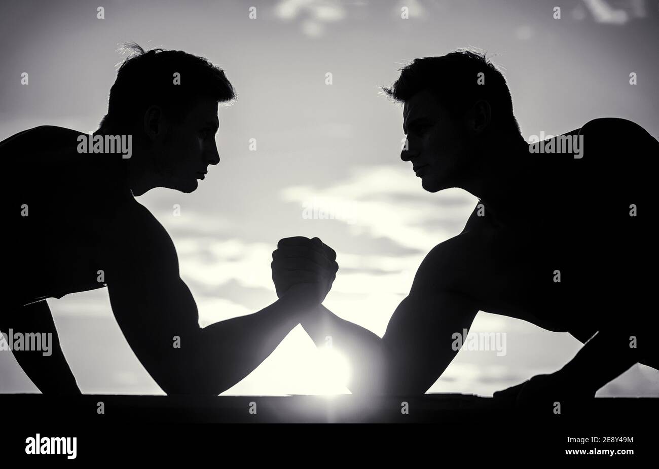 Rivalité, vs, défi, lutte de main. Coucher de soleil, lever du soleil. Silhouette de mains qui rivalisent en force. Rivalité, gros plan de lutte de bras mâle. Noir Banque D'Images