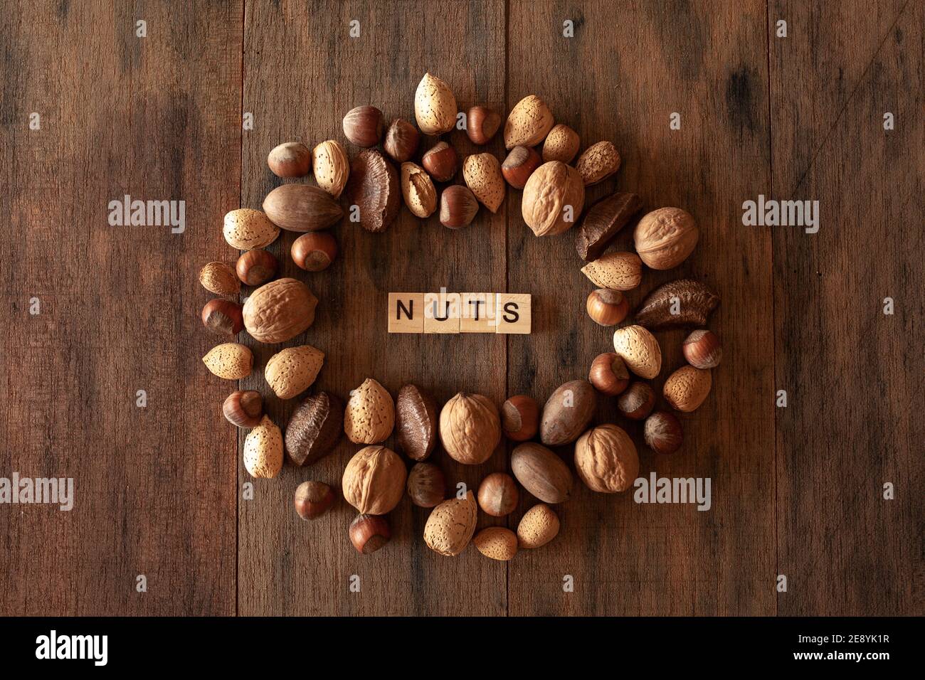 Amandes Shelles, noix, noix de macadamia, pacanes, noisettes disposées en cercle sur fond de bois Banque D'Images