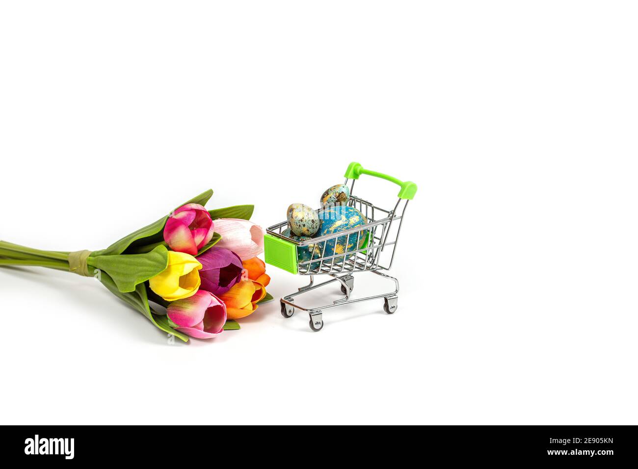 Panier avec œufs de Pâques peints et un bouquet de tulipes isolées sur fond blanc Banque D'Images