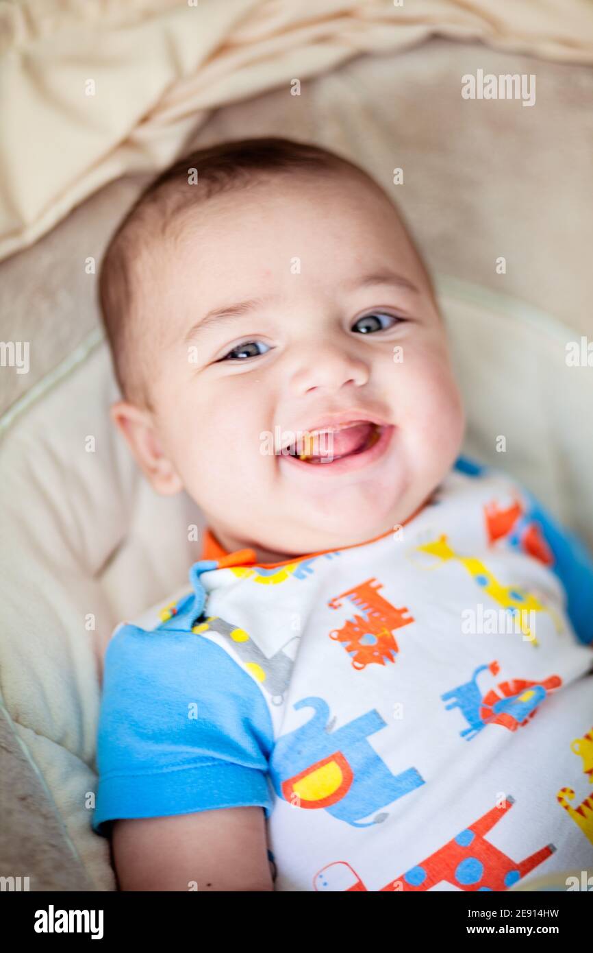 Bébé souriant mangeant son premier repas solide Banque D'Images