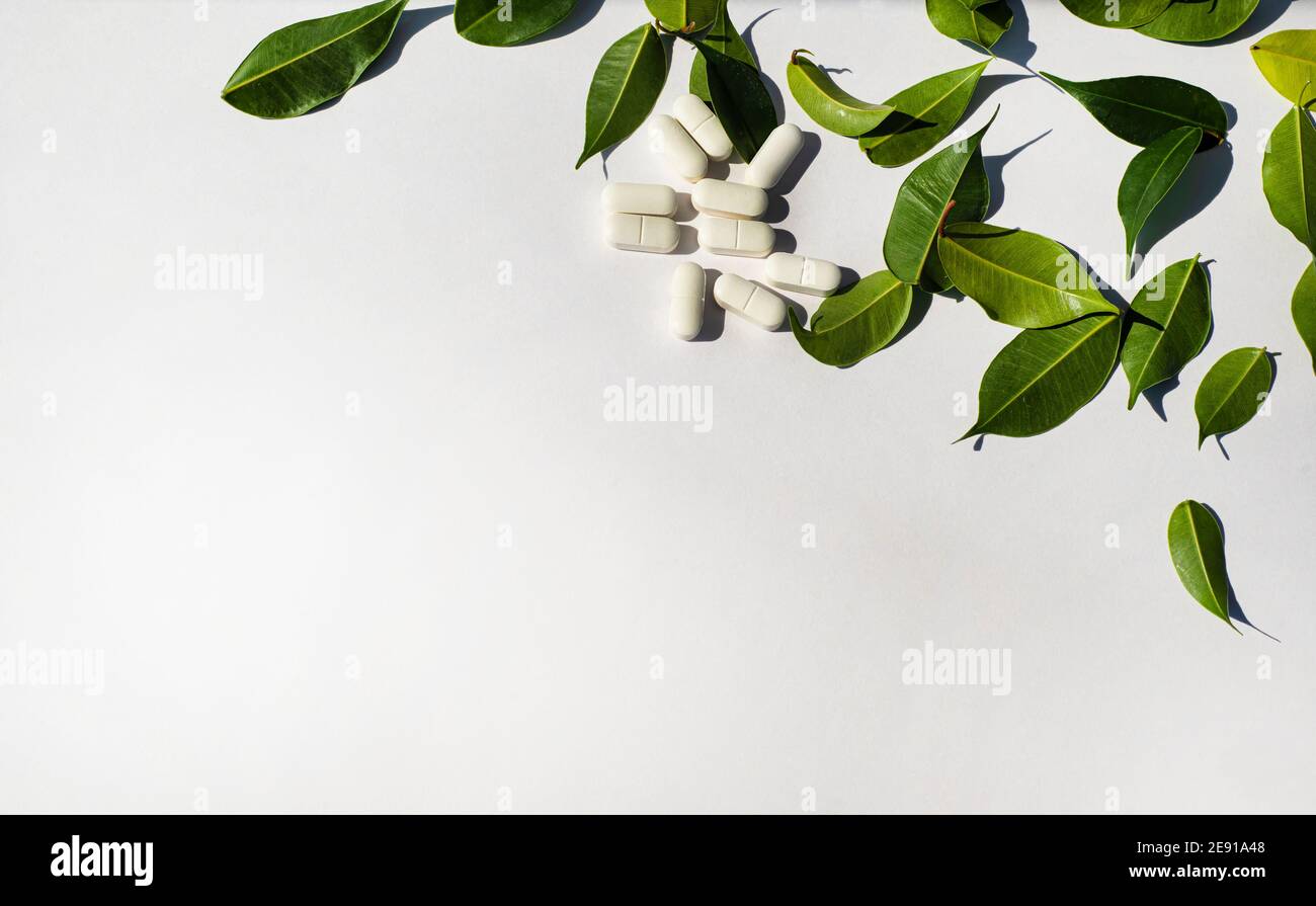 Coin de bordure fait de pilules blanches et de feuilles vertes fraîches. Modèle pour le texte de l'annonce de la note. Thème de la santé et de la nutrition. Banque D'Images