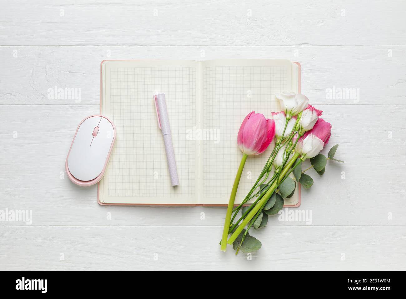 Ordinateur portable, stylo, souris PC et belles fleurs sur fond blanc en bois Banque D'Images
