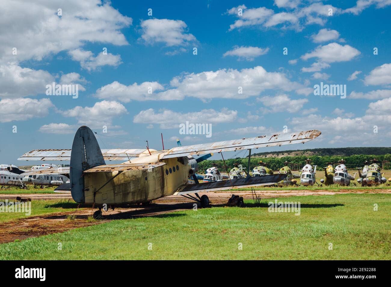 Un vieux avion abandonné, détruit et rouillé se trouve sur l'herbe sous un ciel bleu avec des nuages blancs. Banque D'Images