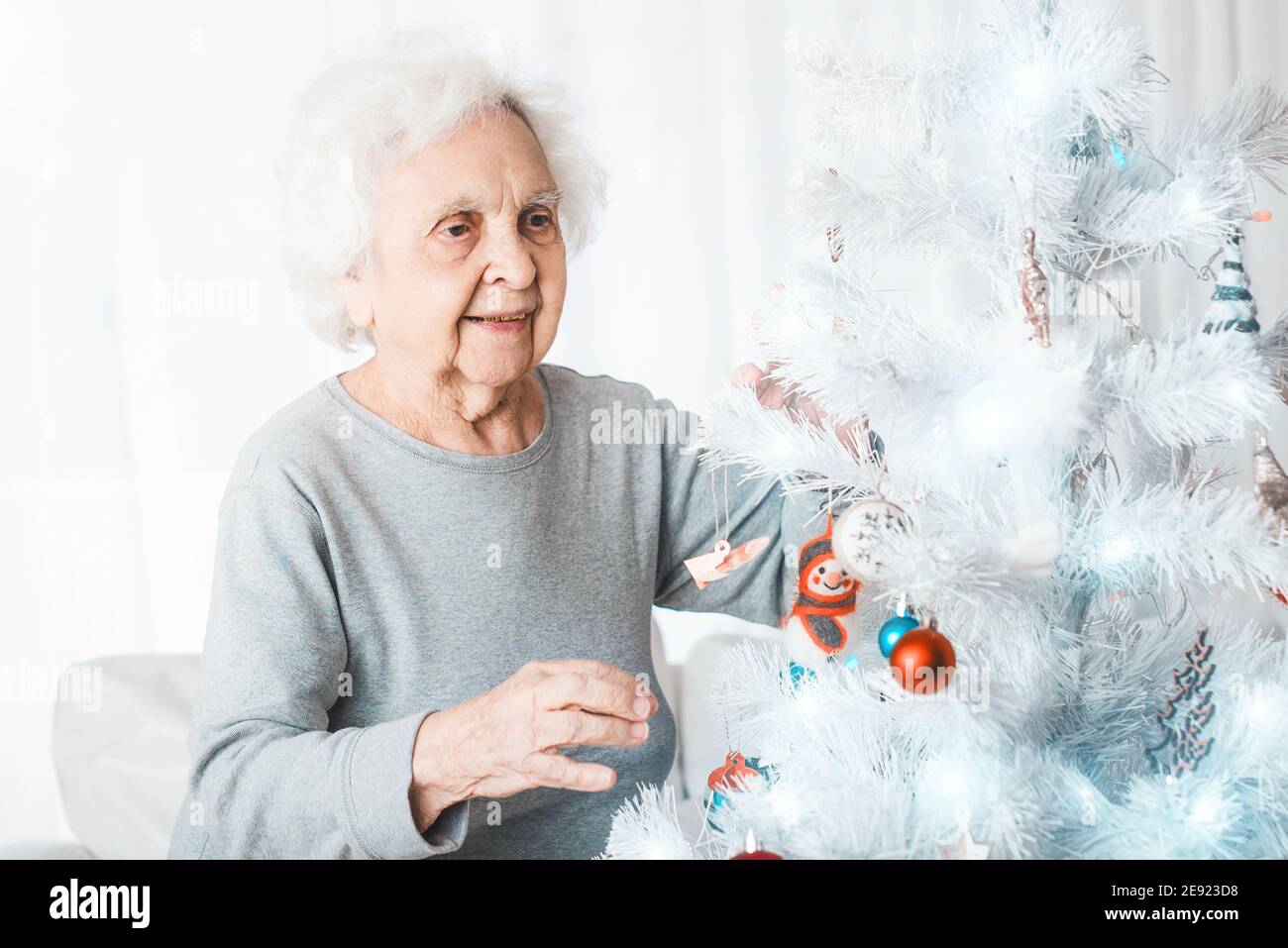 Femme aîée souriante décorant un sapin de noël de fantaisie Banque D'Images