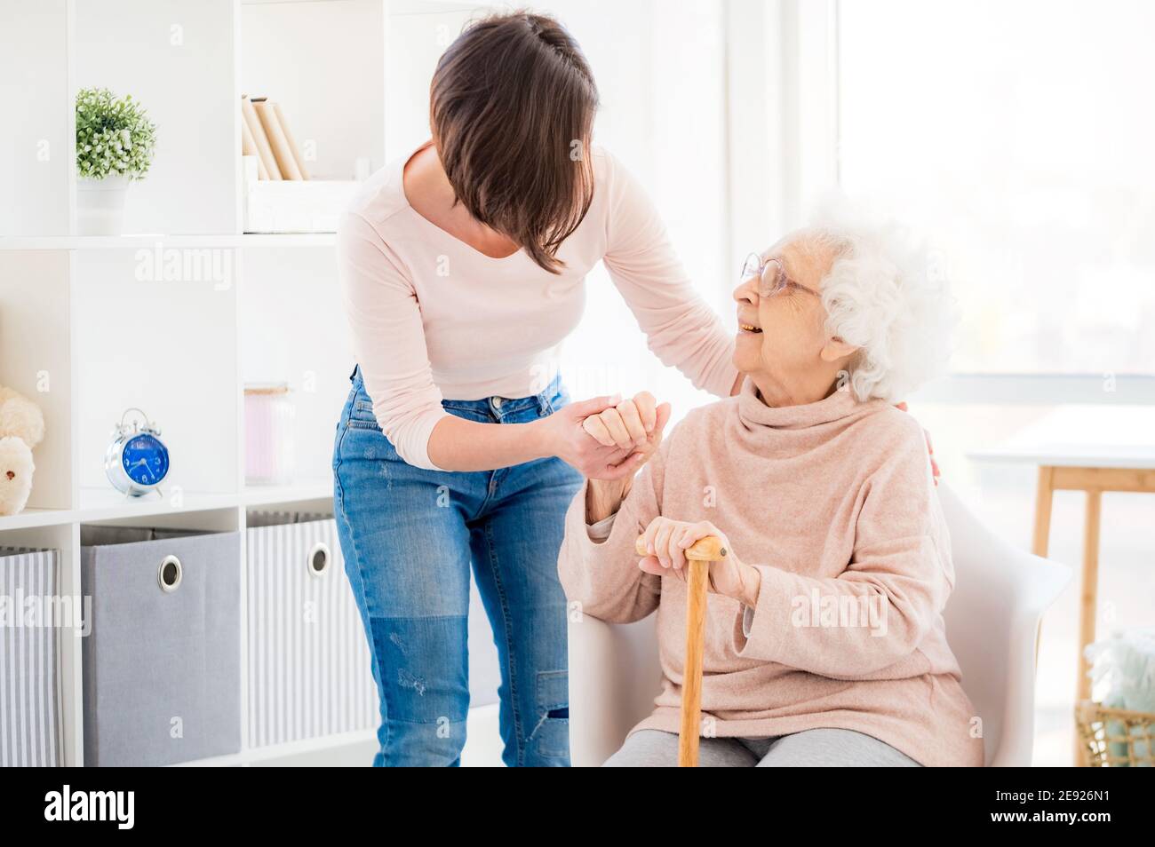 Une femme gentille aidant une vieille dame charmante à se tenir debout de la chaise Banque D'Images