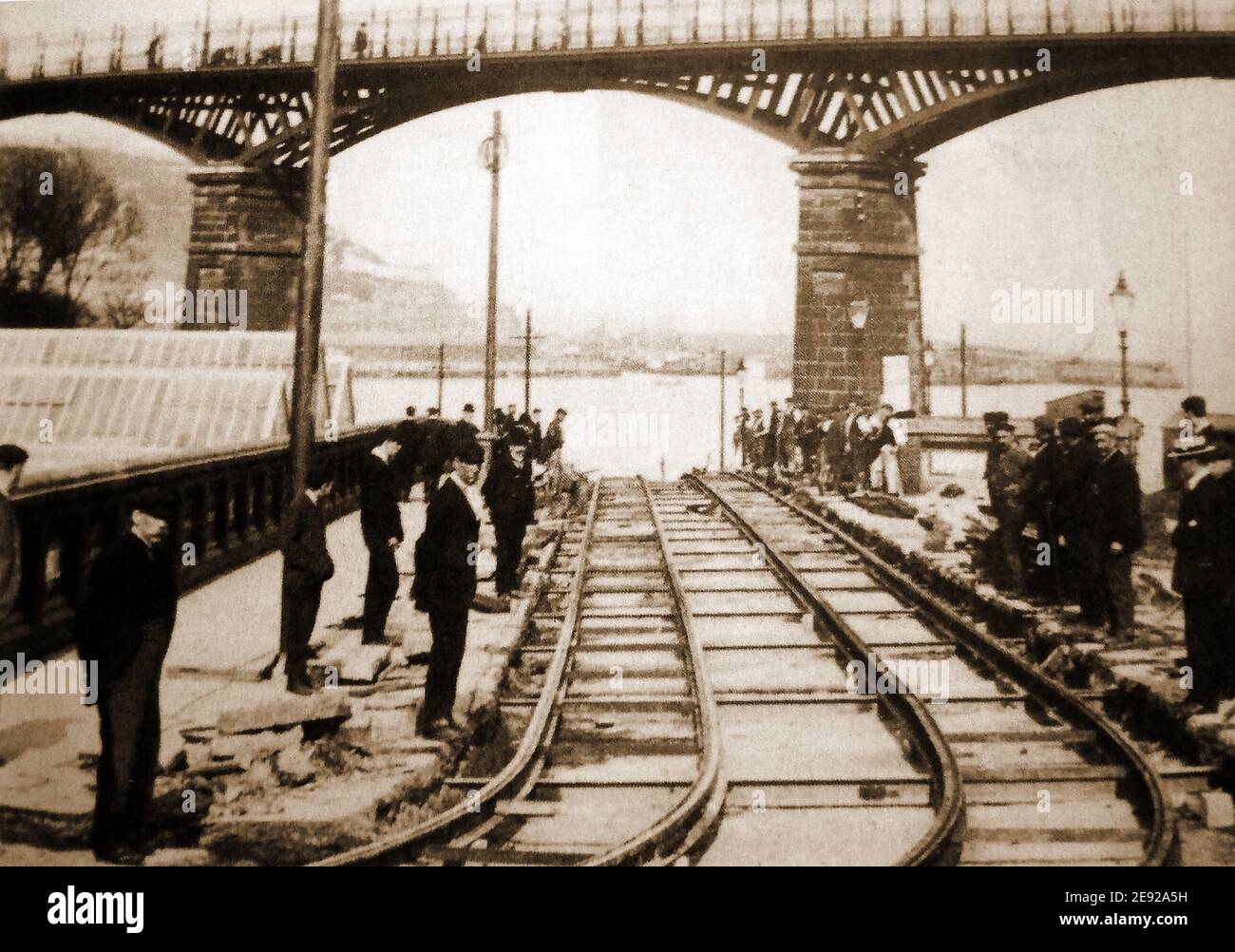 Une ancienne photographie prise à Scarborough, dans le North Yorkshire, au Royaume-Uni, montrant les pistes de tramway récemment mises en place sous Valley Bridge avec des travailleurs, des superviseurs et des observateurs réunis pour une photographie montrant la section terminée. La baie et le port de Scarborough sont visibles en arrière-plan. La construction a commencé le 12 octobre 1903 (ouverte au public le 6 mai 1904) Banque D'Images