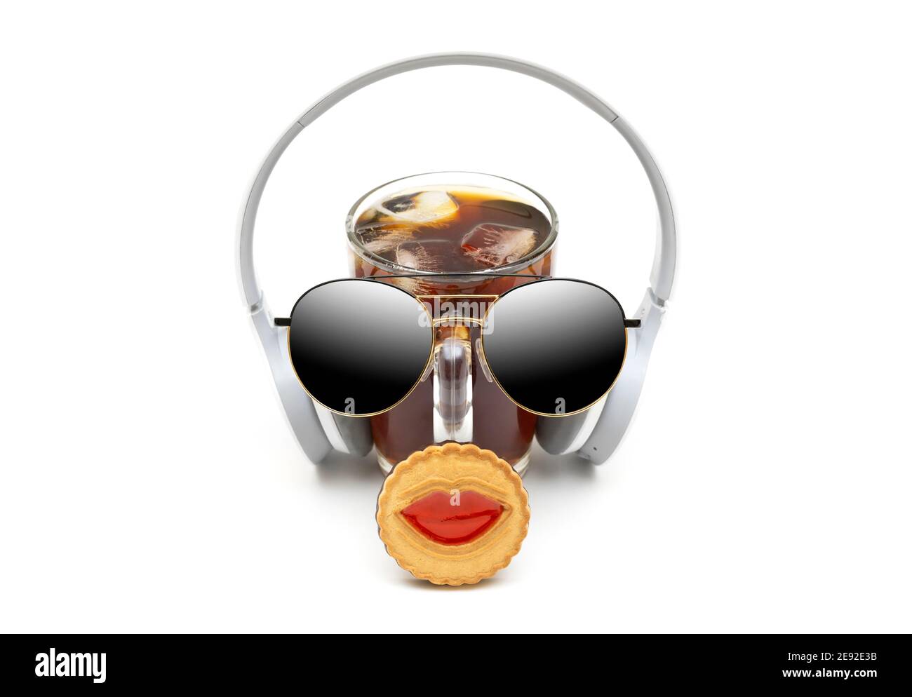 Composition amusante composée d'un verre de café glacé, d'écouteurs, de lunettes de soleil et d'un biscuit aux lèvres. Concept créatif et rafraîchissant. Banque D'Images