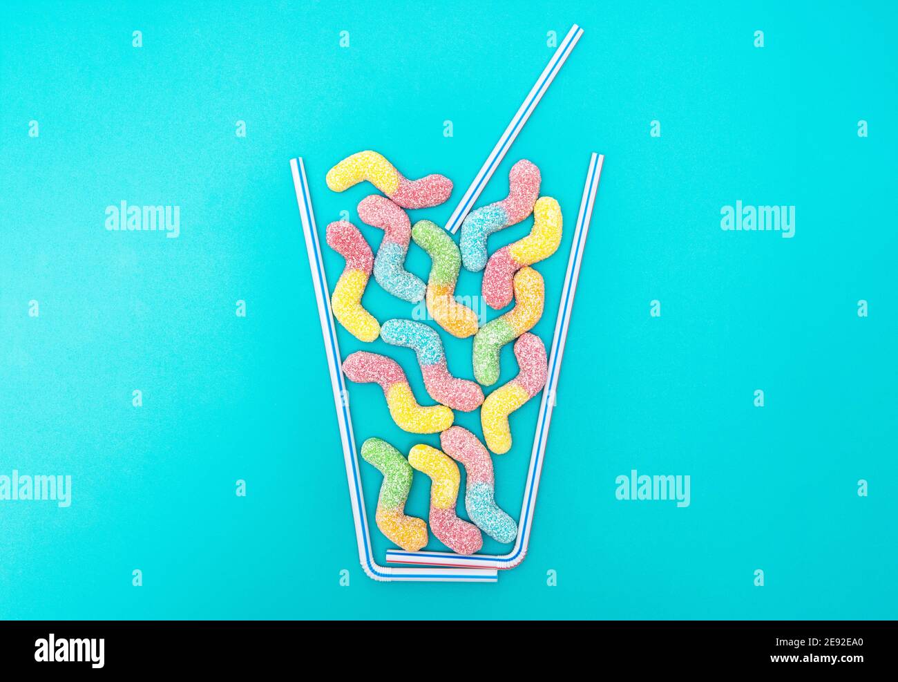 Composition de plat de cocktail d'été créative à base de pailles à boire et vers délicieux enrobés de sucre vif sur fond bleu clair Banque D'Images