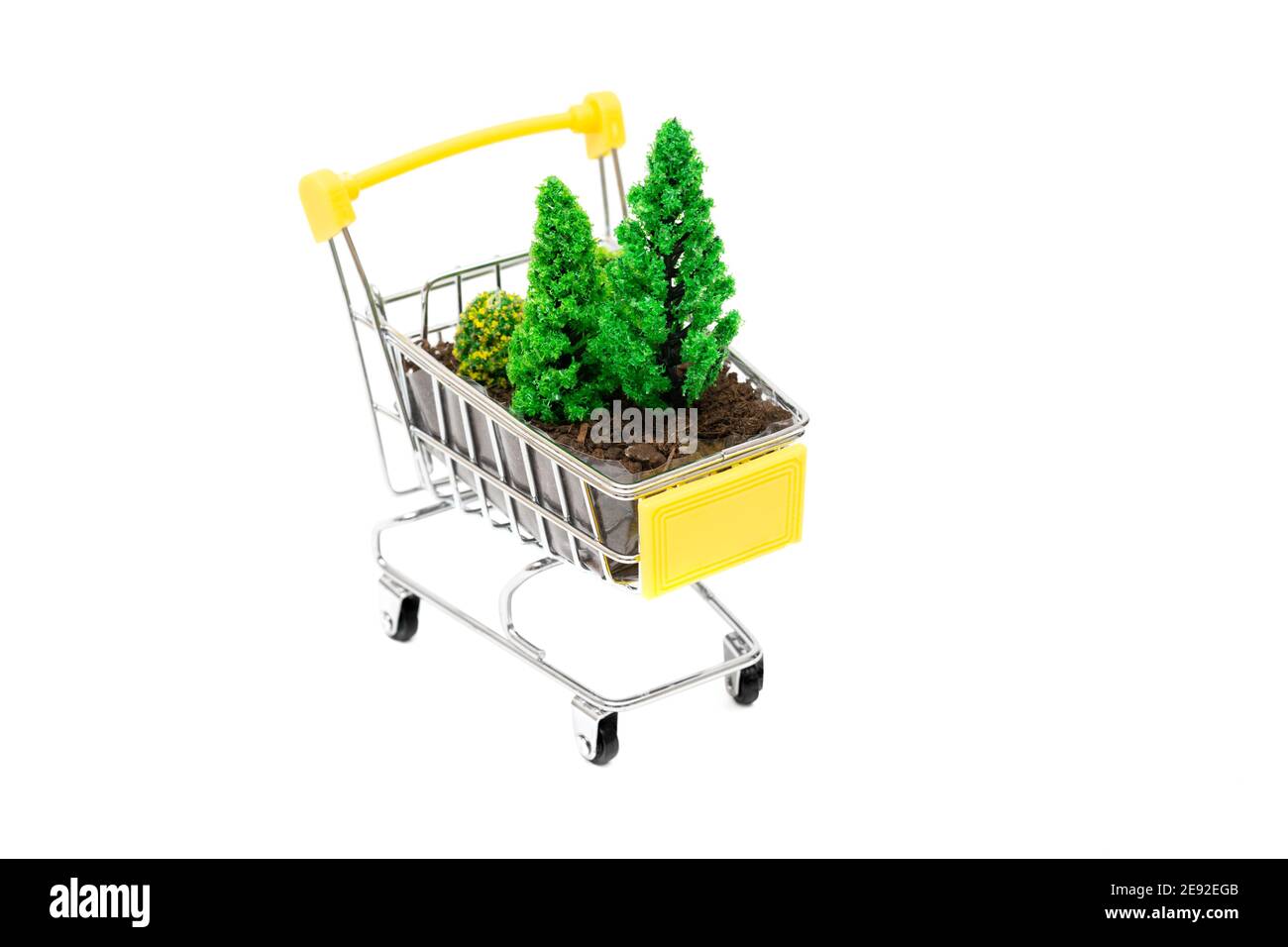 Gros plan d'un petit chariot de shopping avec des arbres de terre et de jouets isolés sur blanc. Concept créatif de soin des forêts. Banque D'Images