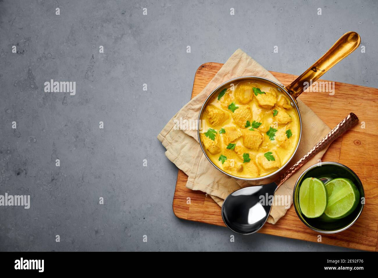 Poulet Korma dans un récipient en cuivre sur une table en béton gris. Cuisine indienne plat de cari à la viande avec masala au lait de coco. Cuisine asiatique. Copier l'espace Banque D'Images