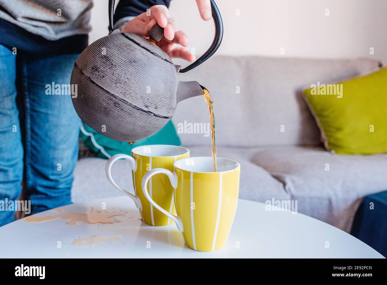 Mains servant le thé d'une bouilloire de fer dans quelques tasses. Thé renversé Banque D'Images Mains servant le thé d'une bouilloire de fer dans quelques tasses. Thé renversé Banque D'Images