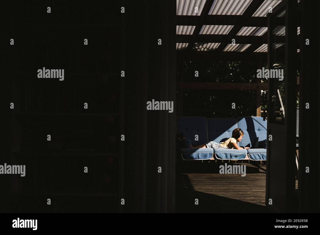 Jeune fille e-learning sur ordinateur portable vu par la porte de la maison Banque D'Images