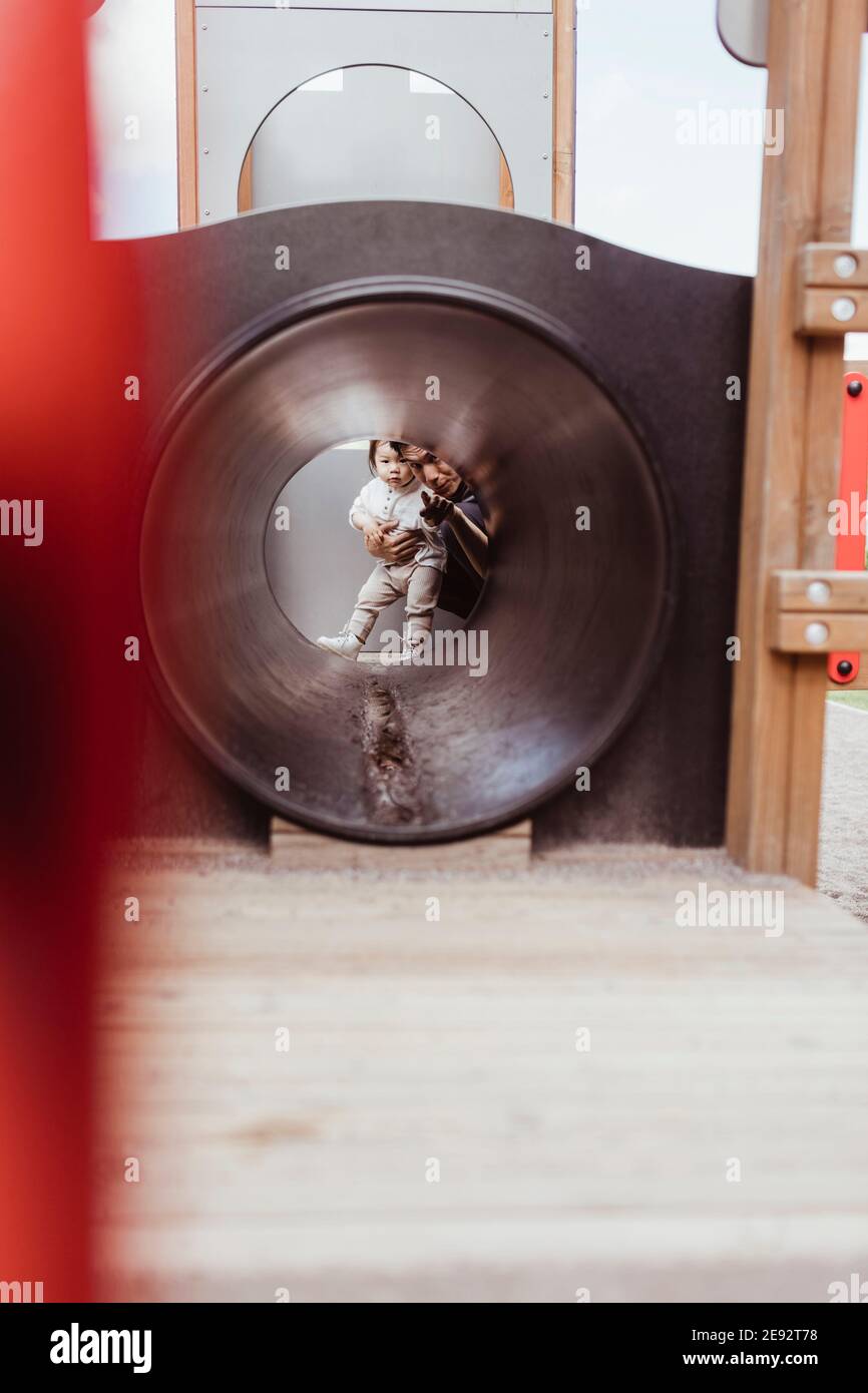 Père et fils vus à travers des équipements de jeu dans le parc Banque D'Images