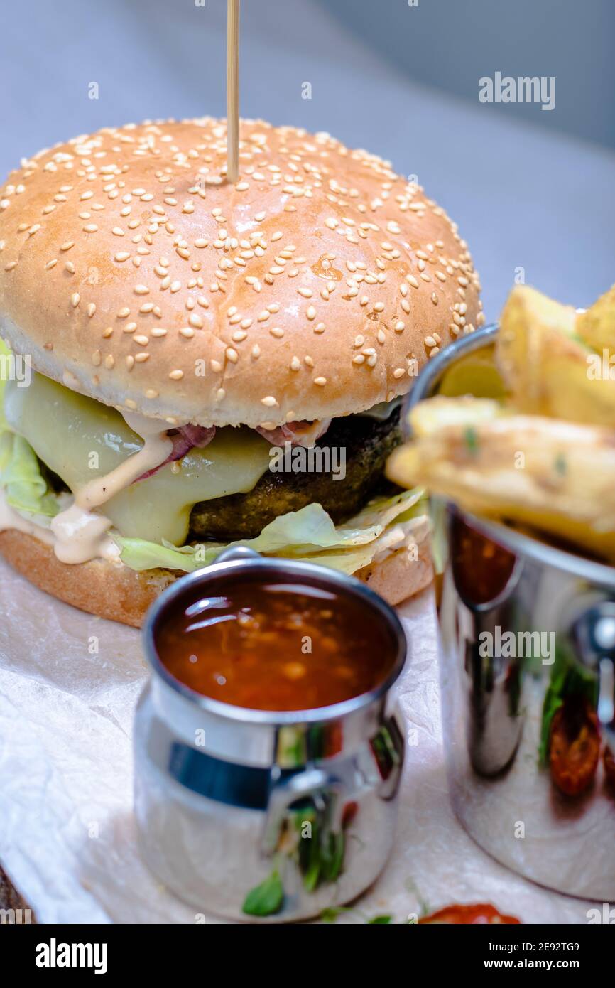 Hamburger et frites avec sauce et tomates sur bois assiette dans un restaurant Banque D'Images