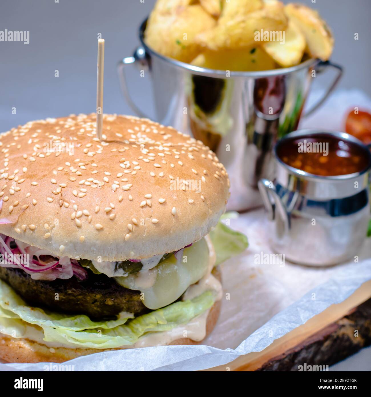 Hamburger et frites avec sauce et tomates sur bois assiette dans un restaurant Banque D'Images