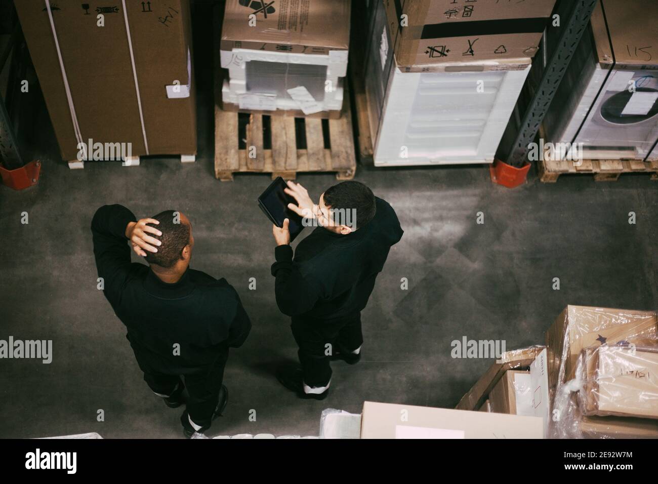 Vue en grand angle de l'employé discutant sur une tablette numérique à l'entrepôt Banque D'Images