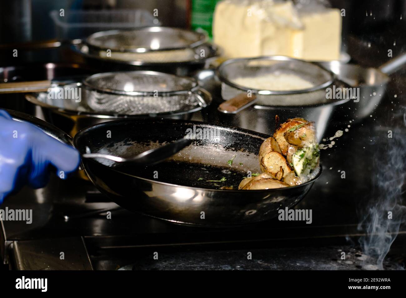 Chef friture des quartiers de pommes de terre sur une poêle en fonte à un restaurant Banque D'Images