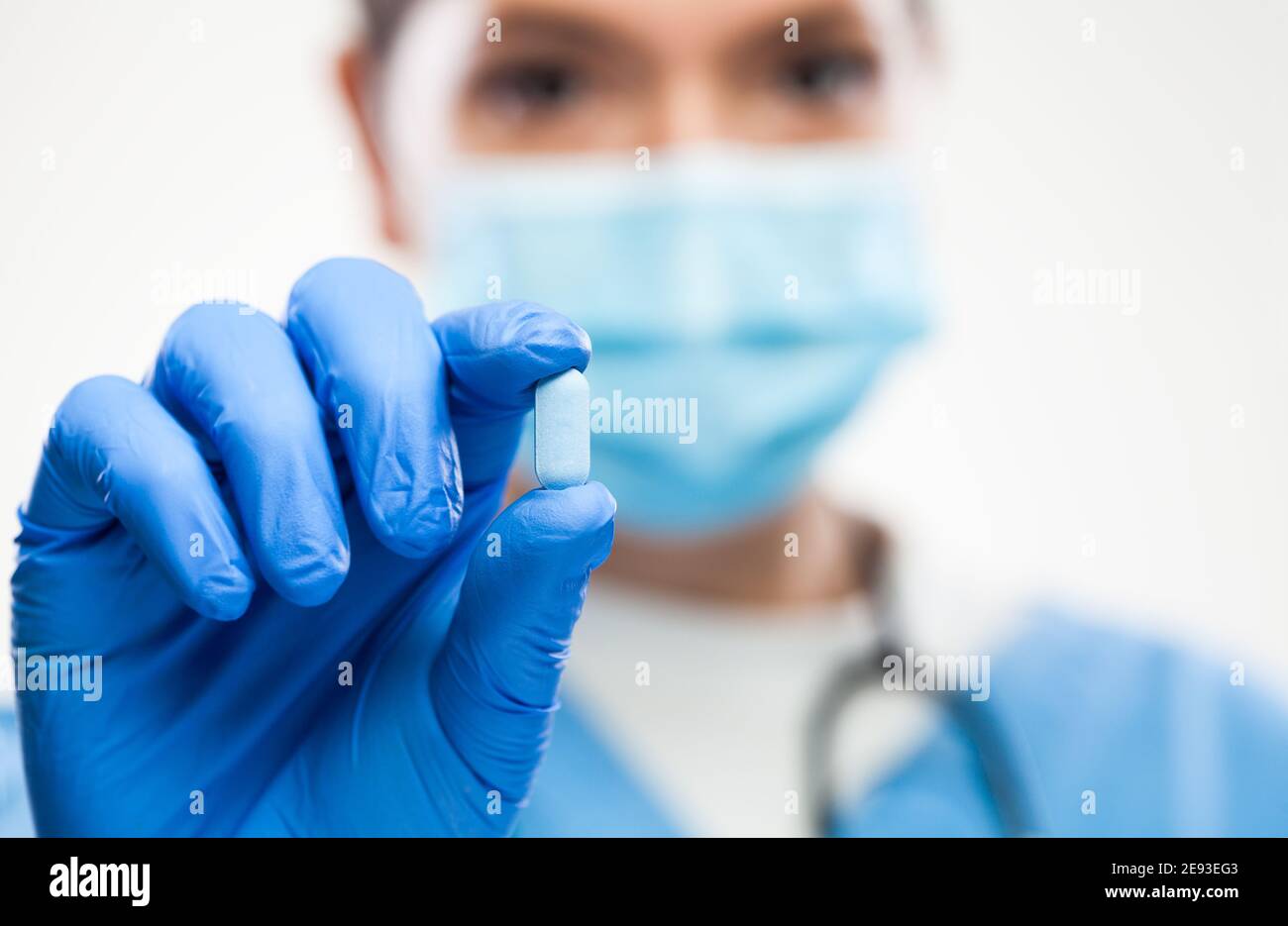 Médecin généraliste britannique NHS GP portant un visage protecteur masque,gants,tenue de pilule bleue,macro sélective focus de détail, traitement du patient et rémed Banque D'Images