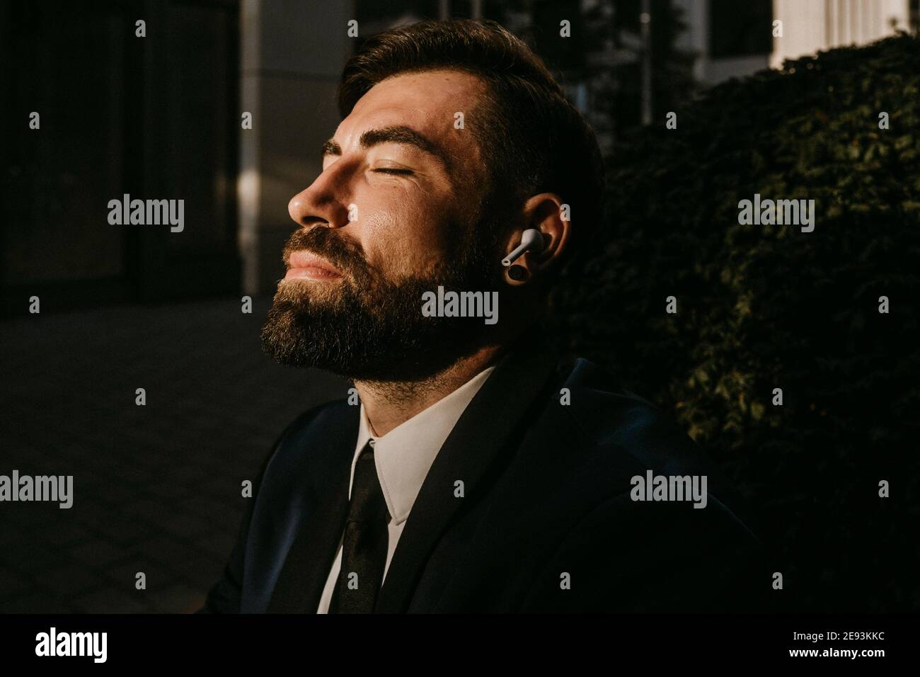 Homme d'affaires avec les yeux fermés écouter de la musique par des écouteurs sans fil Banque D'Images